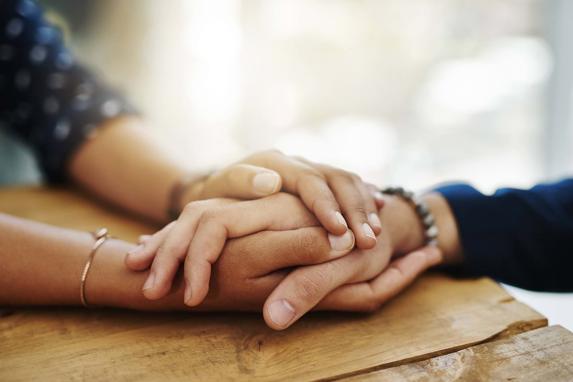 two people hold hands in a consoling way